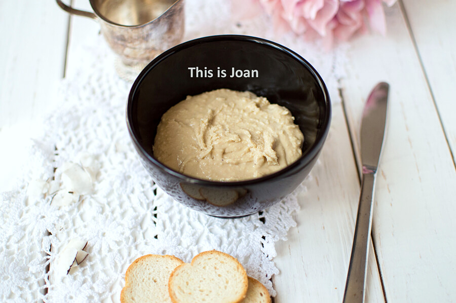 een wit kleedje met daarop een zwart, rond bakje met zelfgemaakte cashewpasta