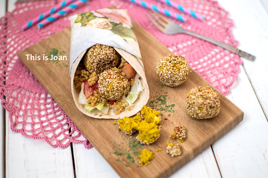 een roze kleedje met daarop een snijdplank met een wrap en vier balletjes glutenvrije falafel