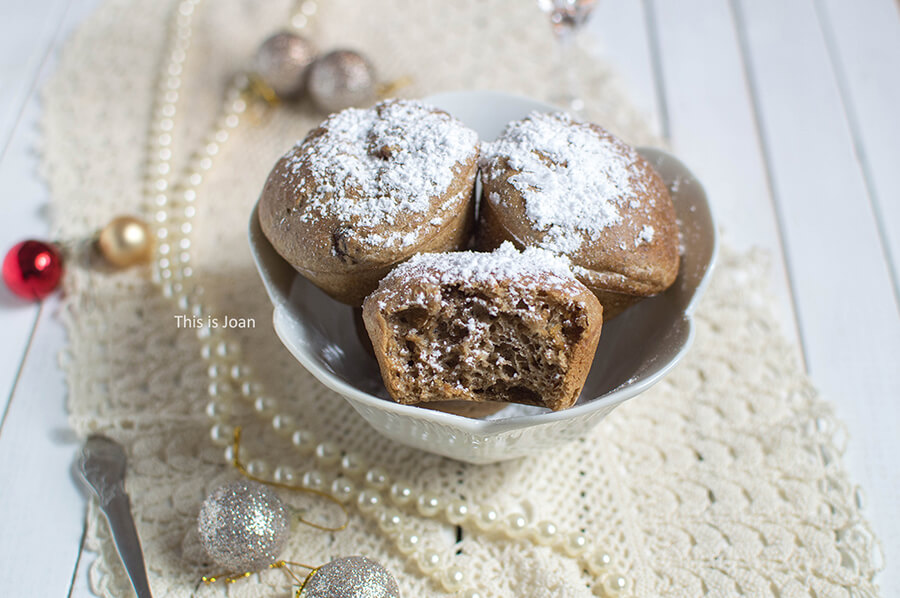 een beige kleed met daarop een witte kom met daarin 3 oliebollen uit de oven die zijn bestrooid met poedersuiker